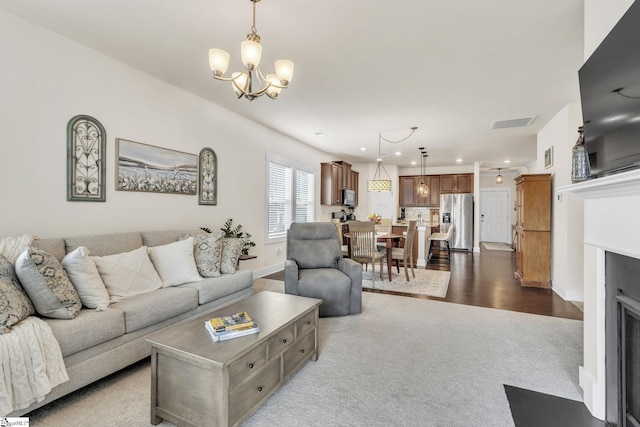 living area featuring recessed lighting, dark colored carpet, visible vents, a fireplace with flush hearth, and a chandelier