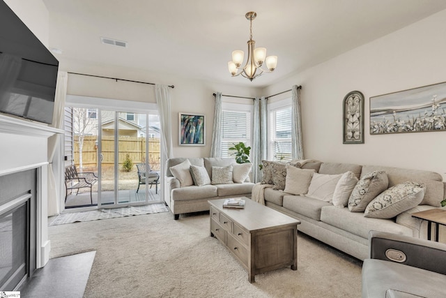 living room featuring a fireplace with flush hearth, light colored carpet, a chandelier, and visible vents