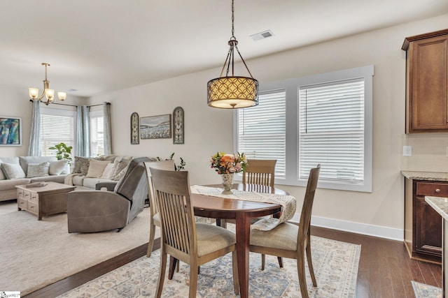 dining space with baseboards, visible vents, a chandelier, and dark wood-style flooring