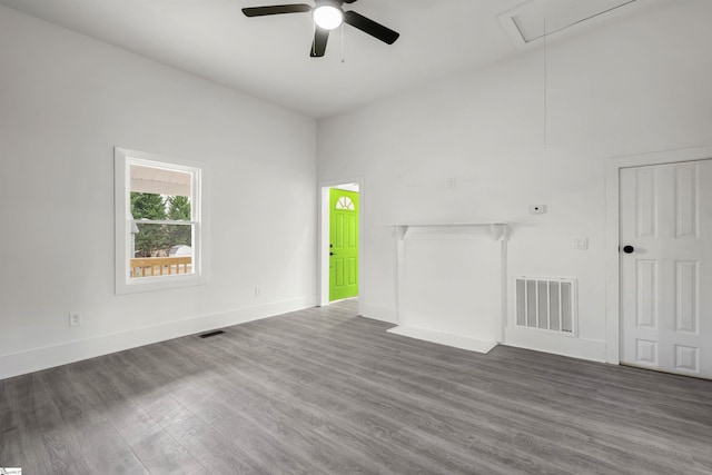 unfurnished living room with attic access, visible vents, baseboards, and wood finished floors