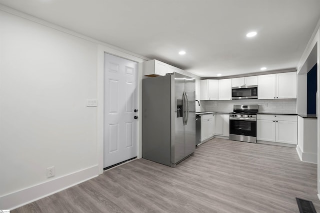 kitchen with light wood-style flooring, stainless steel appliances, visible vents, white cabinets, and tasteful backsplash