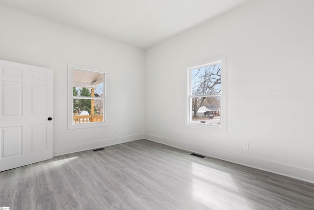 spare room with visible vents, baseboards, and wood finished floors