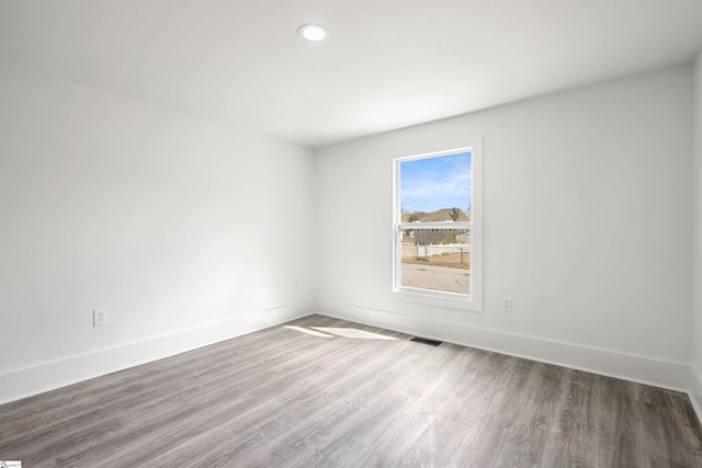 empty room featuring recessed lighting, visible vents, baseboards, and wood finished floors