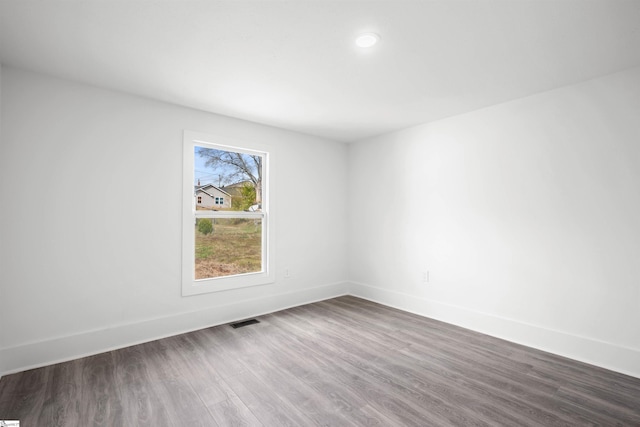 unfurnished room with baseboards, visible vents, and dark wood-type flooring