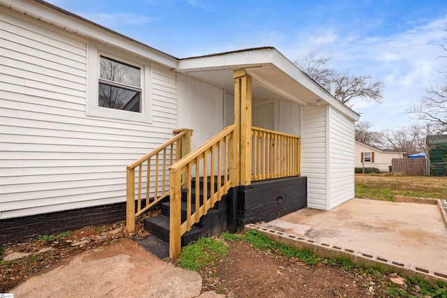 view of exterior entry with a patio and fence