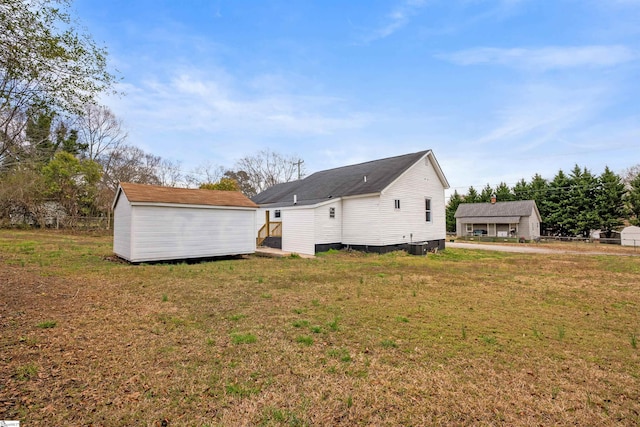 back of property featuring a storage shed, a lawn, and an outdoor structure