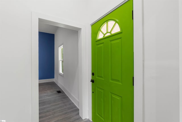 foyer with dark wood-type flooring, visible vents, and baseboards