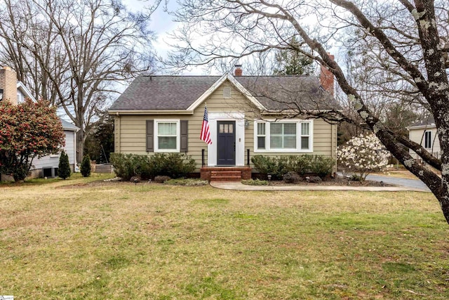 bungalow-style home with a chimney, a front lawn, and roof with shingles