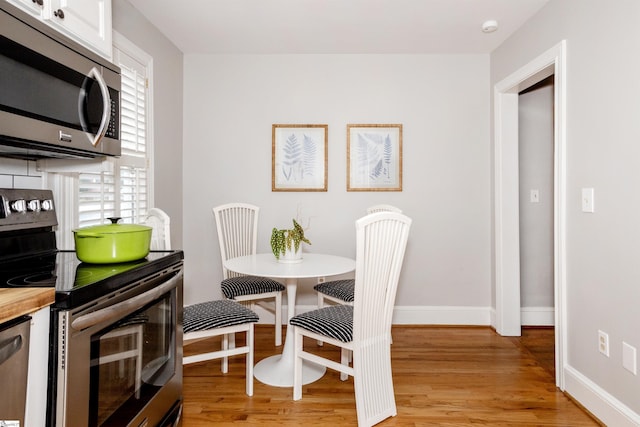 dining area with light wood-type flooring and baseboards