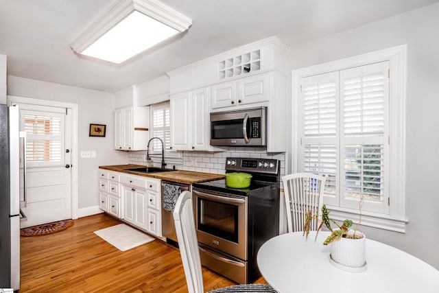 kitchen with appliances with stainless steel finishes, a wealth of natural light, butcher block countertops, and a sink