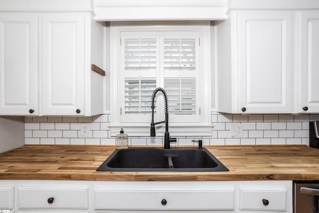 kitchen featuring white cabinets, wooden counters, and a sink