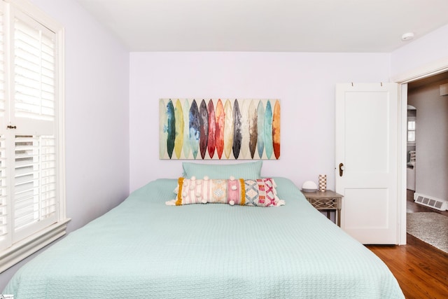 bedroom with visible vents, multiple windows, and wood finished floors