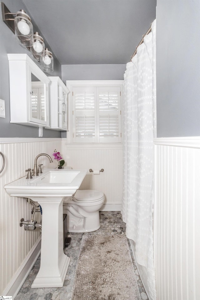 bathroom featuring wainscoting, toilet, and a shower with curtain