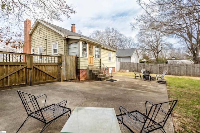 back of house with entry steps, a patio, a fenced backyard, roof with shingles, and a gate