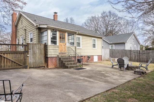 back of property with entry steps, a patio, fence, a gate, and a chimney