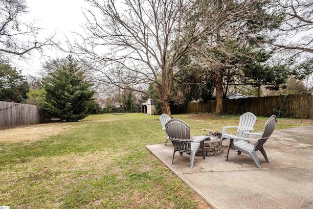 view of yard featuring a patio area, a fenced backyard, a storage unit, and an outbuilding