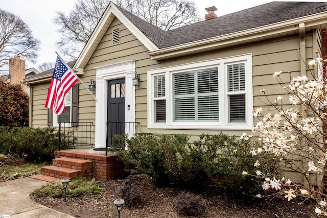 view of front of home featuring a shingled roof and a chimney