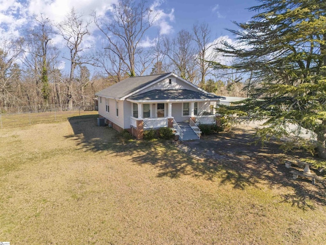 view of front facade with a porch, central AC unit, fence, driveway, and a front yard