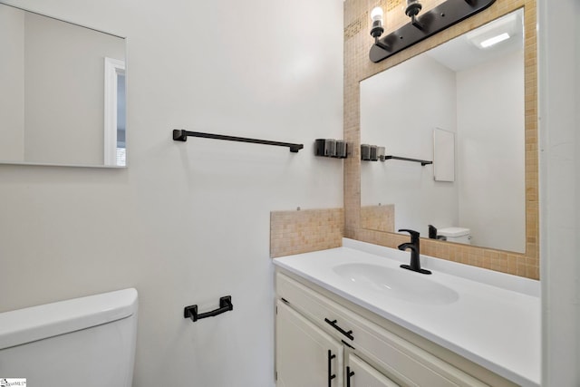 bathroom featuring toilet, backsplash, and vanity