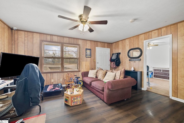 living room with ceiling fan, wooden walls, baseboards, and dark wood-type flooring