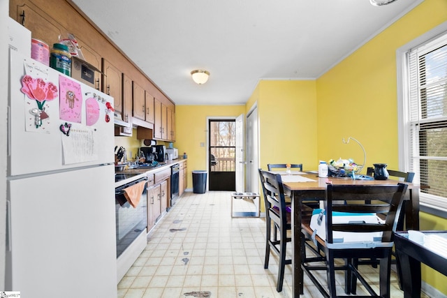 kitchen with white appliances, range hood, brown cabinetry, and light floors