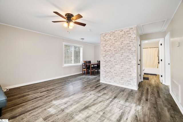 spare room featuring attic access, visible vents, a ceiling fan, wood finished floors, and crown molding