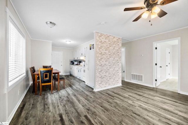 dining space with ceiling fan, visible vents, baseboards, dark wood-style floors, and crown molding