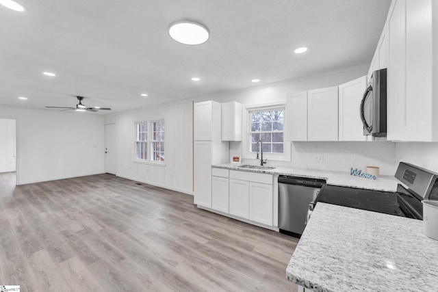 kitchen featuring stainless steel appliances, a sink, light wood-style flooring, and white cabinetry