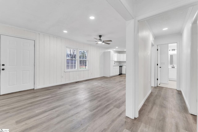 unfurnished living room with ceiling fan, light wood-type flooring, baseboards, and crown molding