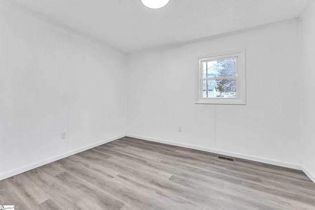 empty room with ornamental molding, visible vents, baseboards, and wood finished floors