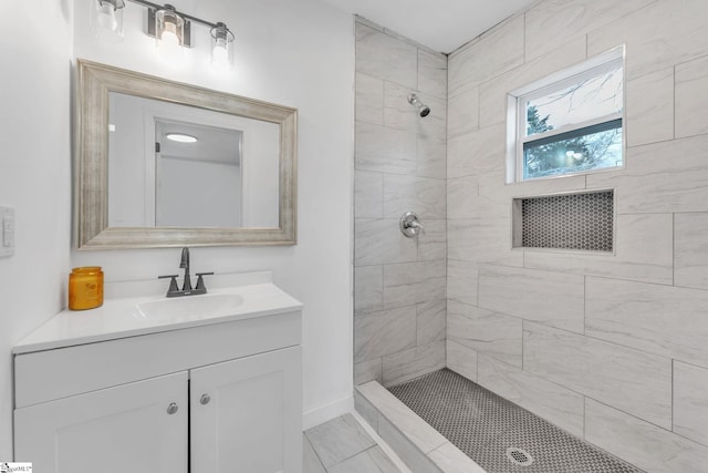 full bath with tiled shower, vanity, and baseboards