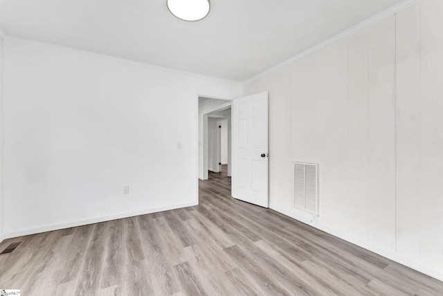 spare room featuring ornamental molding, visible vents, baseboards, and wood finished floors