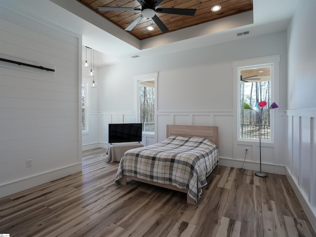 bedroom with a barn door, wood finished floors, wood ceiling, visible vents, and a raised ceiling