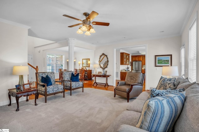 living area featuring light colored carpet, crown molding, baseboards, and ceiling fan