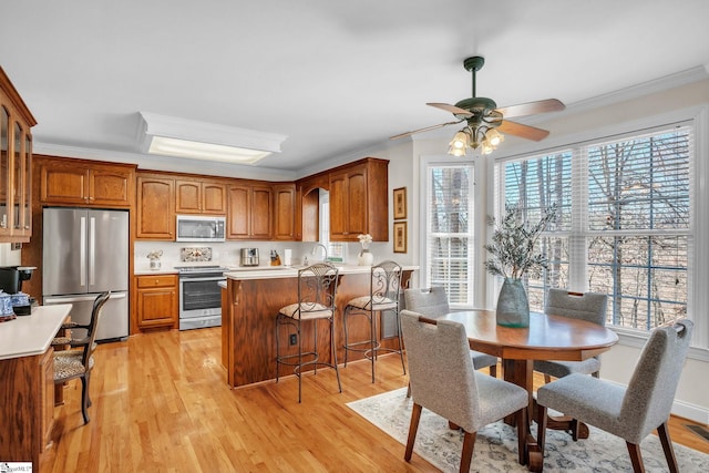 kitchen with brown cabinets, light wood finished floors, a peninsula, and stainless steel appliances