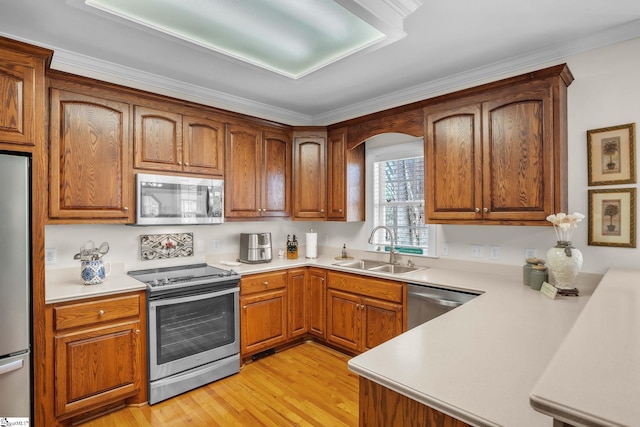 kitchen with light wood finished floors, appliances with stainless steel finishes, light countertops, and a sink