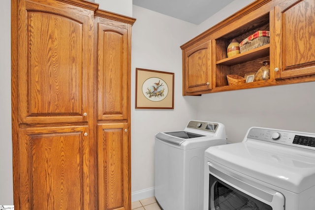 laundry room with light tile patterned floors, washing machine and dryer, cabinet space, and baseboards