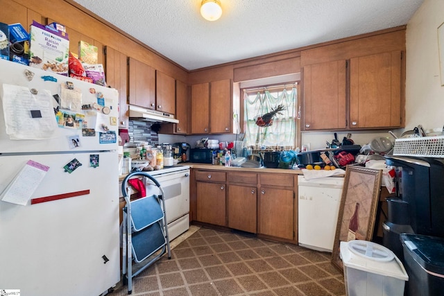 kitchen featuring white appliances, dark floors, brown cabinets, a textured ceiling, and under cabinet range hood