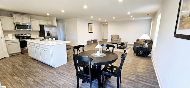 dining space with baseboards, wood finished floors, and recessed lighting