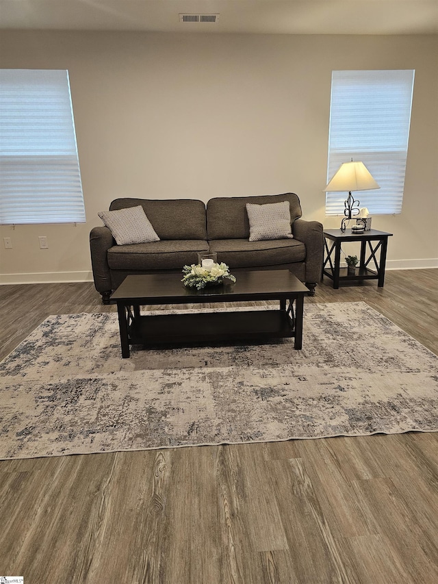 living area with wood finished floors, visible vents, and baseboards