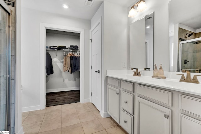 full bath featuring double vanity, a stall shower, a sink, and tile patterned floors