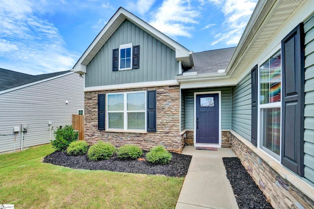 property entrance featuring board and batten siding, stone siding, and a yard