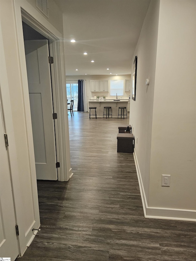 hall with recessed lighting, a sink, visible vents, baseboards, and dark wood-style floors