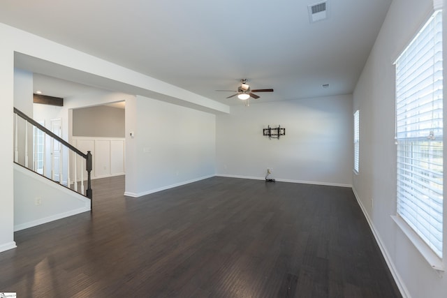 interior space featuring dark wood finished floors, visible vents, stairway, a ceiling fan, and baseboards