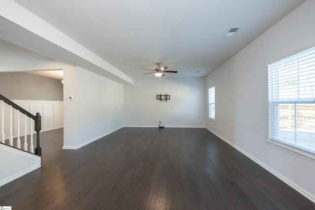 unfurnished living room featuring visible vents, dark wood-type flooring, a ceiling fan, baseboards, and stairs