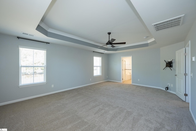 empty room featuring baseboards, visible vents, a raised ceiling, and a ceiling fan