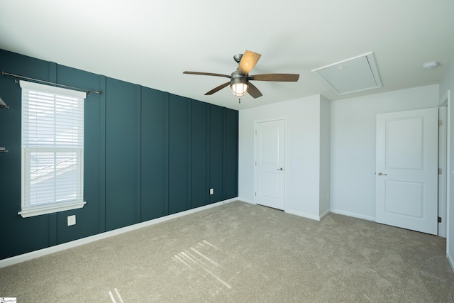 unfurnished bedroom featuring carpet floors, a ceiling fan, and attic access