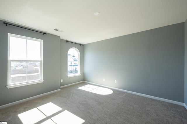 carpeted empty room featuring baseboards and visible vents