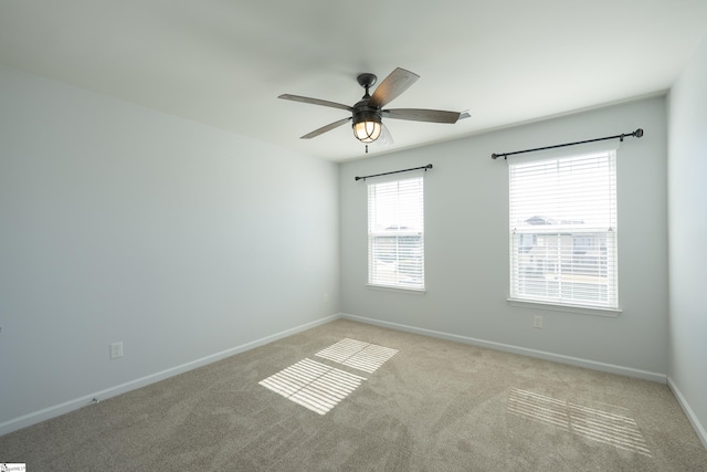 carpeted spare room featuring a ceiling fan and baseboards