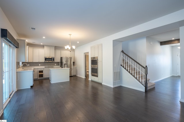 kitchen with visible vents, a kitchen island, stainless steel appliances, light countertops, and a sink